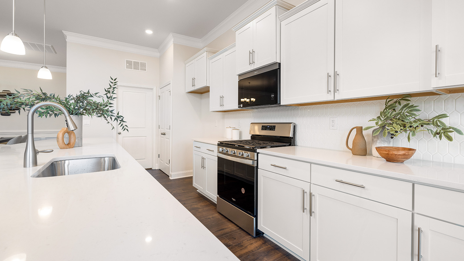 Kitchen and island with wood floors, white cabinets and counters, stainless steel appliances, and seating at island bar