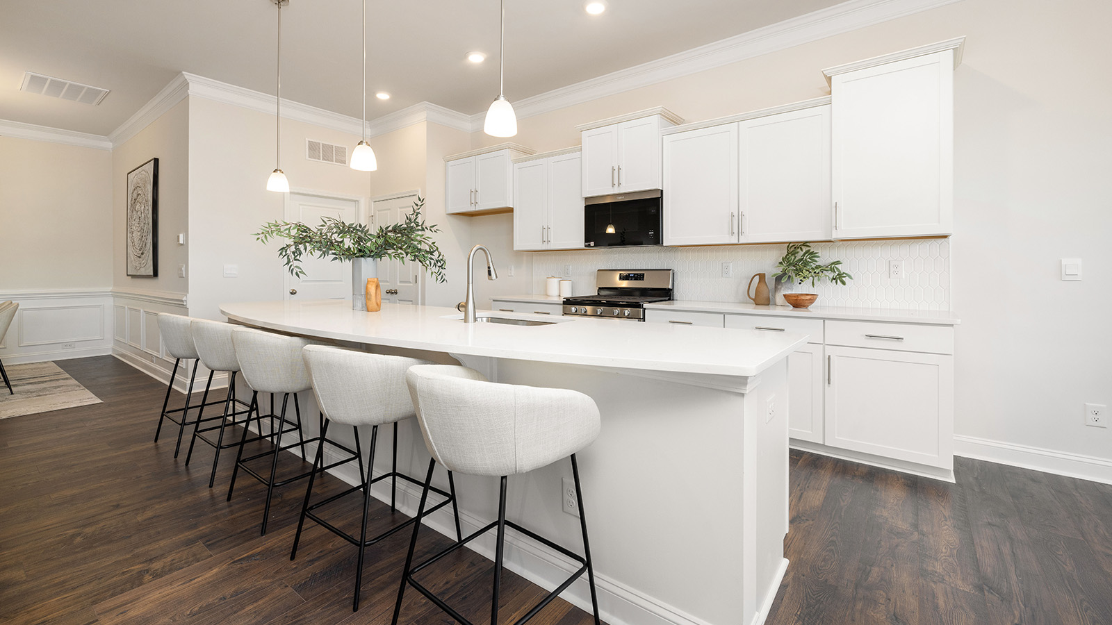Kitchen and island with wood floors, white cabinets and counters, stainless steel appliances, and seating at island bar