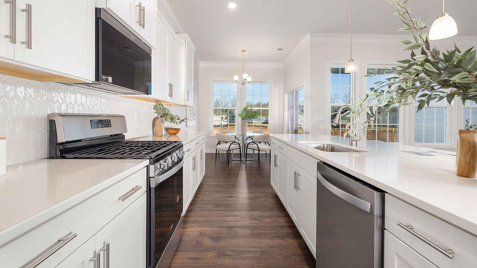 Kitchen and island with wood floors, white cabinets and counters, stainless steel appliances, and seating at island bar