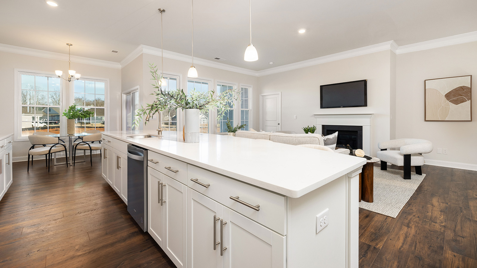 Kitchen and island with wood floors, white cabinets and counters, stainless steel appliances, and seating at island bar