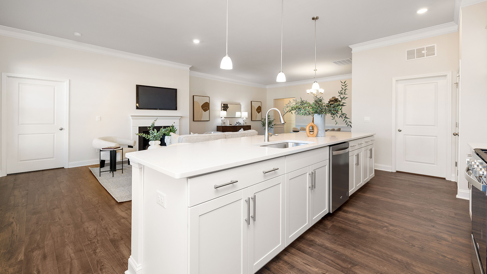 Kitchen and island with wood floors, white cabinets and counters, stainless steel appliances, and seating at island bar