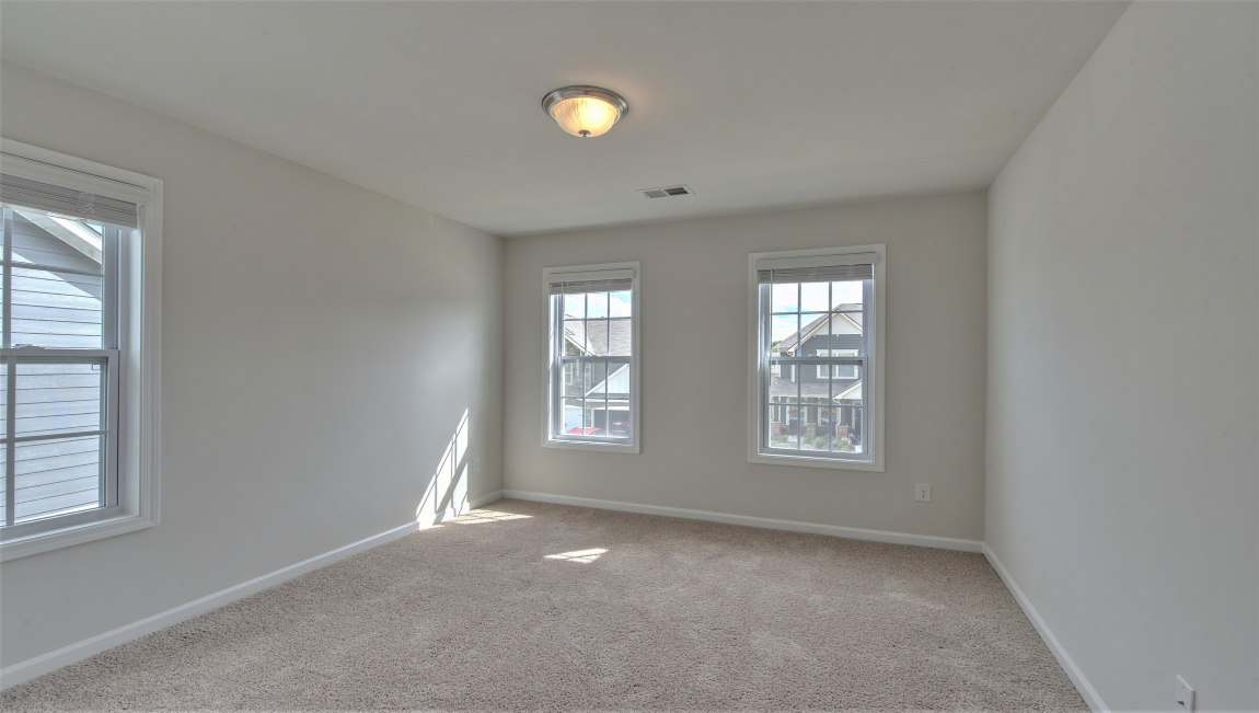 Large carpeted bedroom with multiple windows