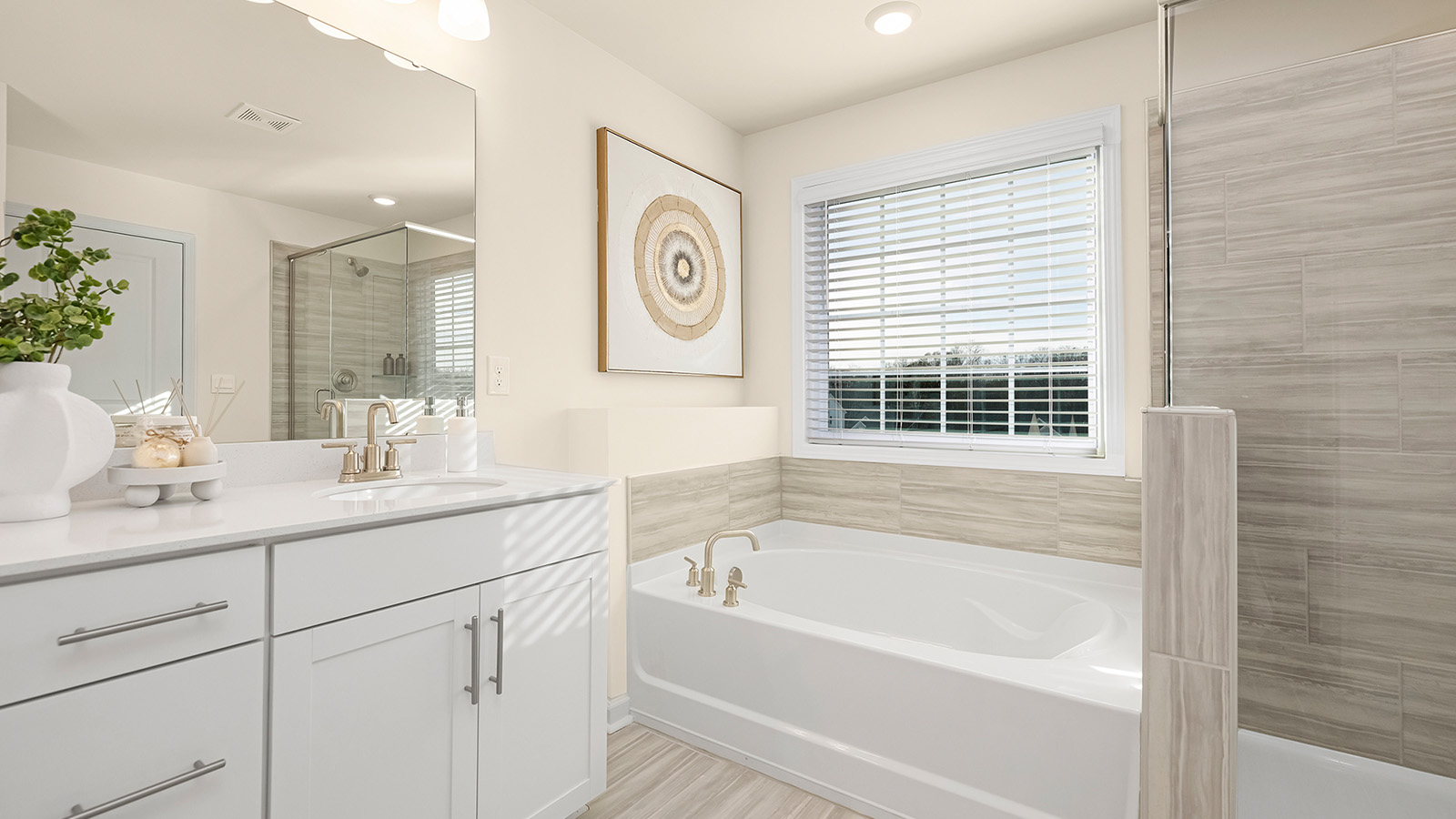 Primary bathroom with white cabinets, bathtub, and glass door shower