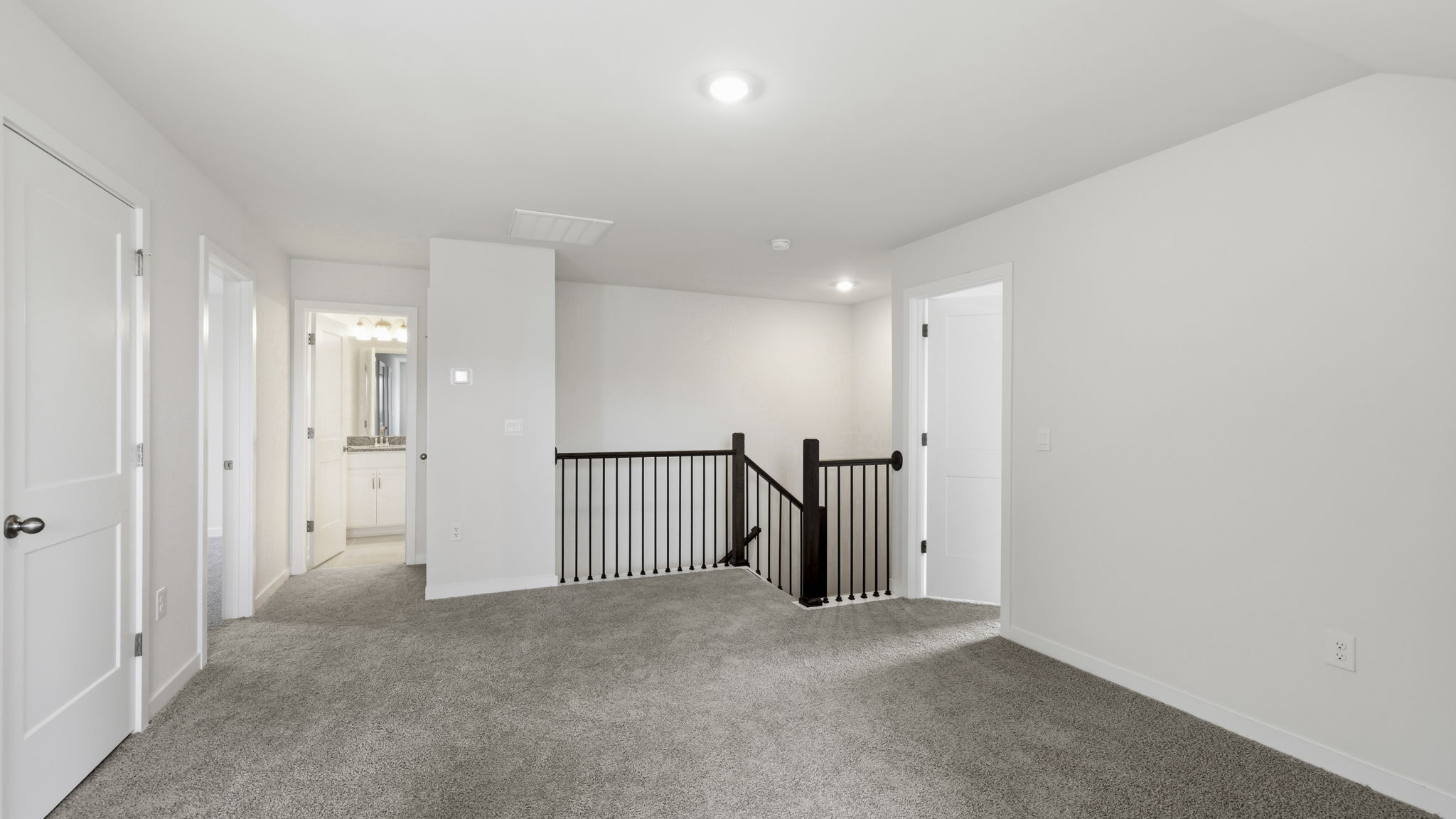 Carpeted loft area with view of stairs
