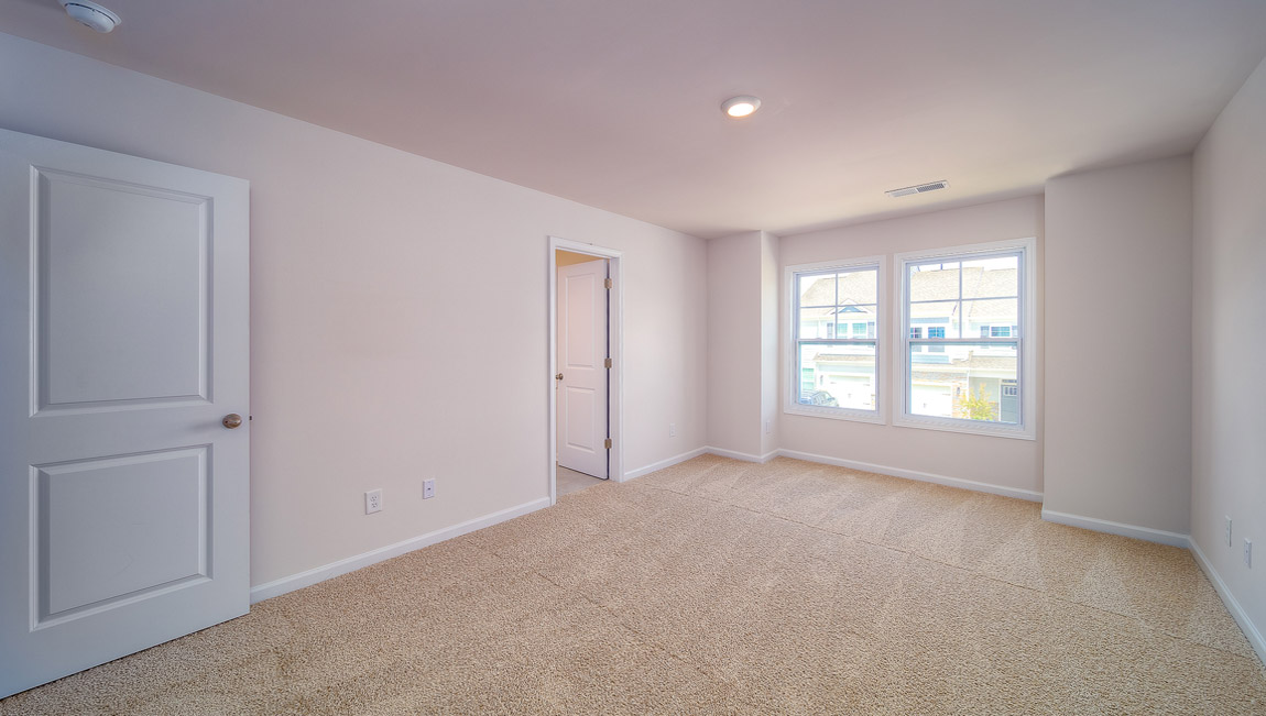 Carpeted primary bedroom with large windows