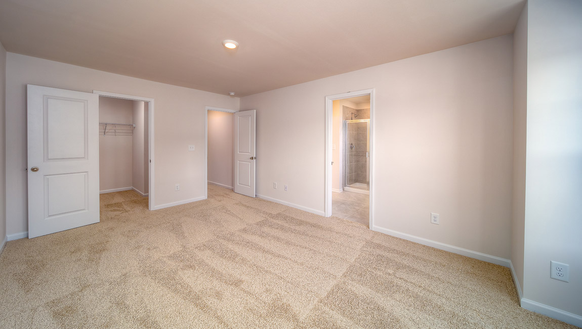Carpeted primary bedroom with large windows