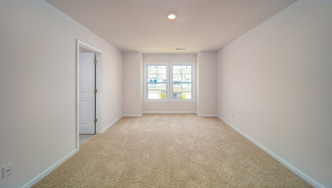 Carpeted primary bedroom with large windows