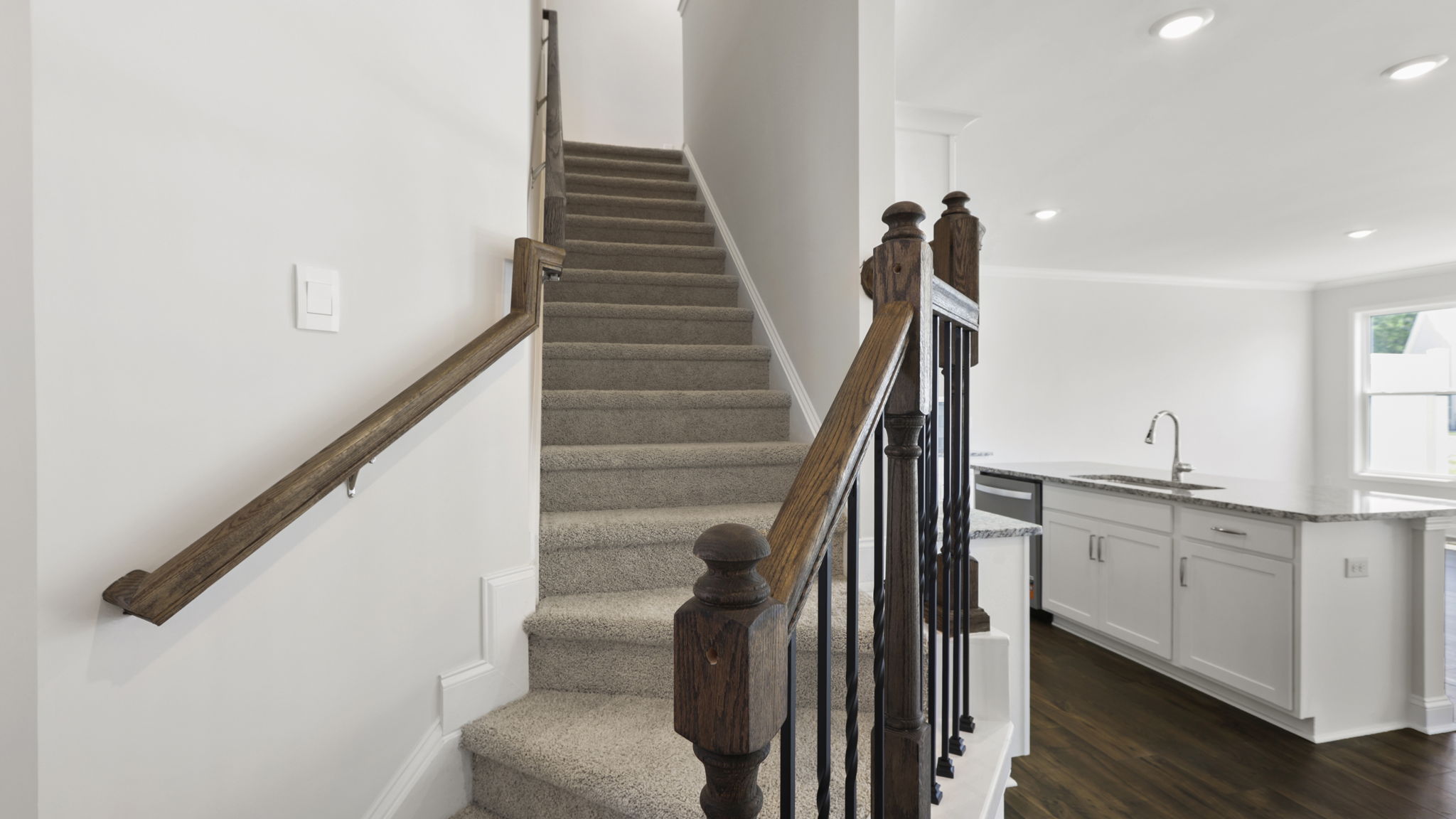 Carpeted stairwell with view of open kitchen area