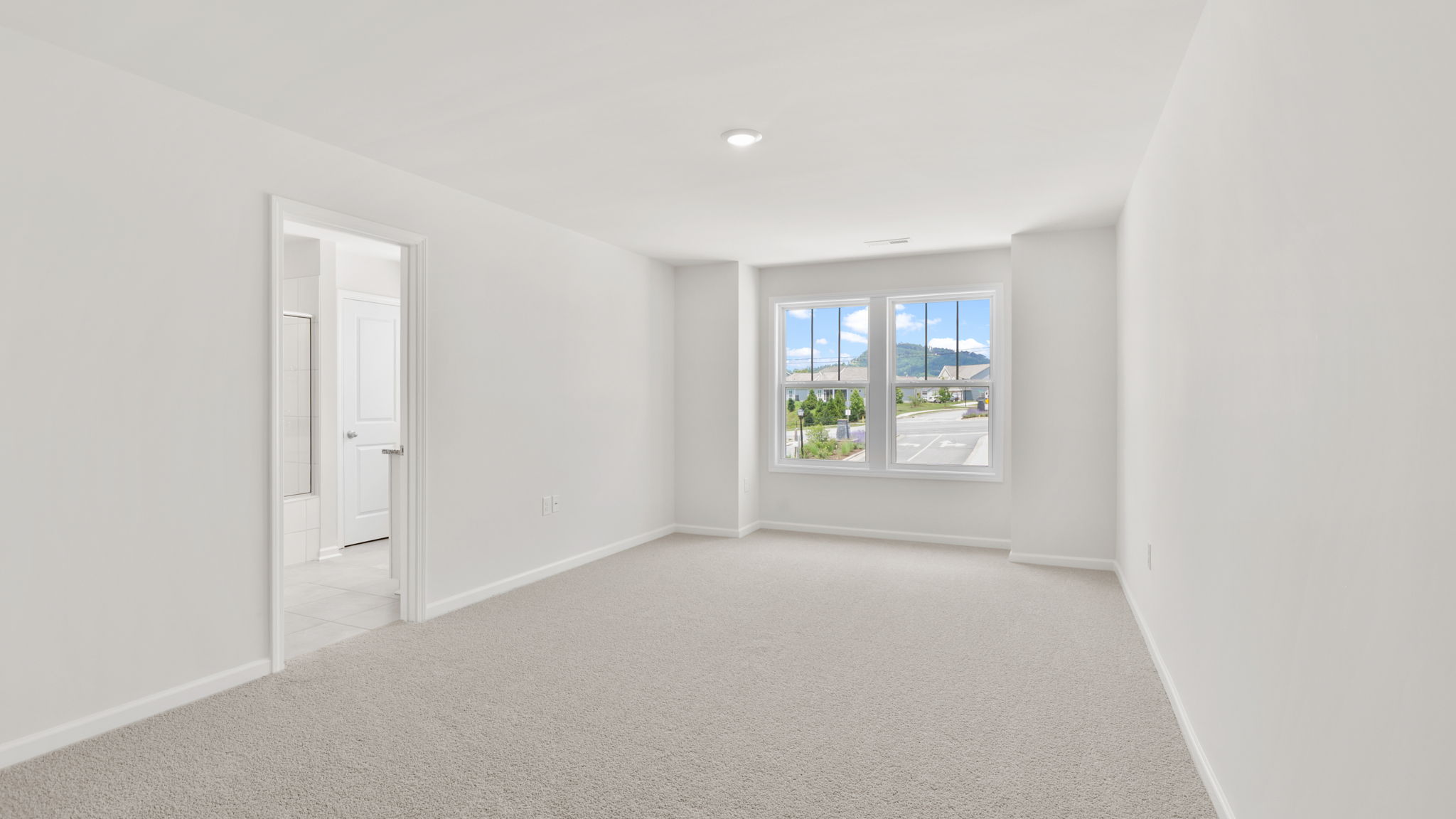 Carpeted primary bedroom with large windows and ensuite bathroom