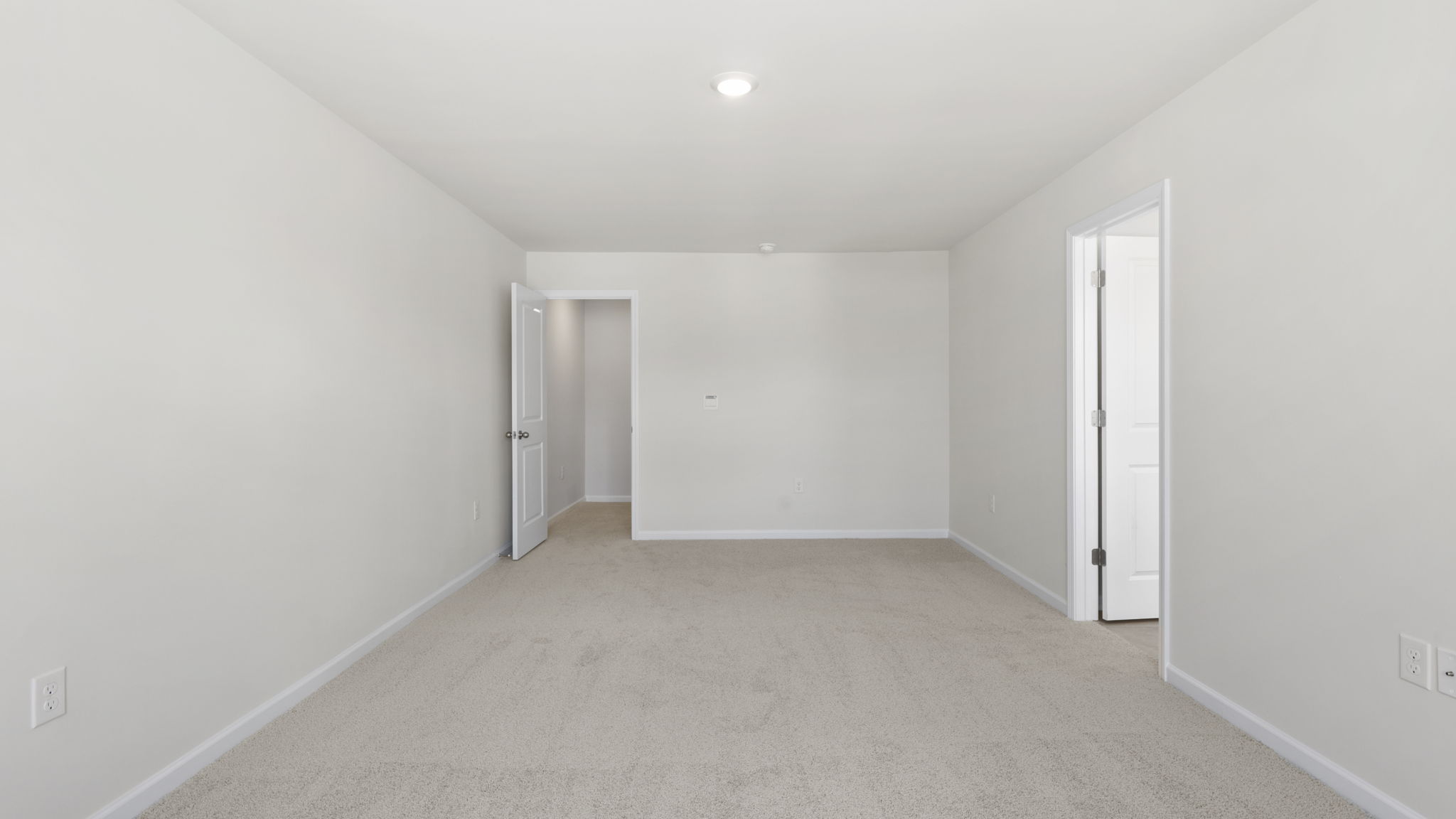 Carpeted primary bedroom with views of bathroom
