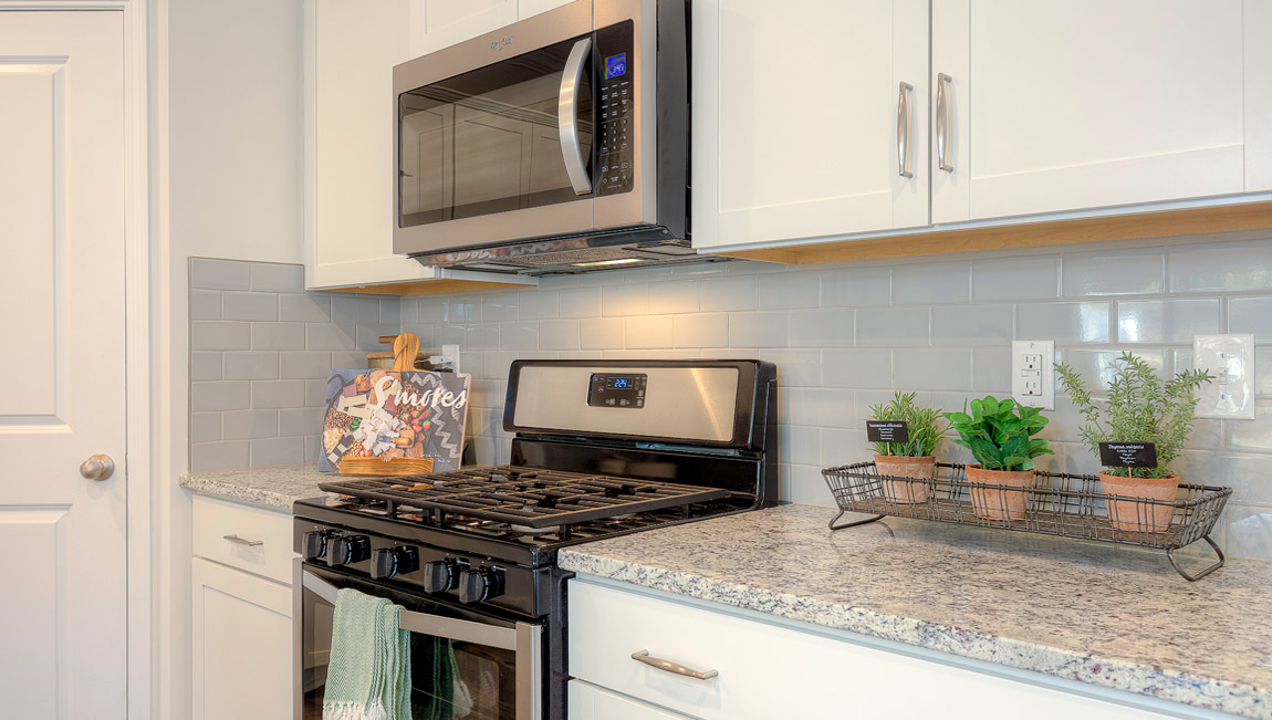 Kitchen and island with wood floors, white cabinets, and stainless steel appliances