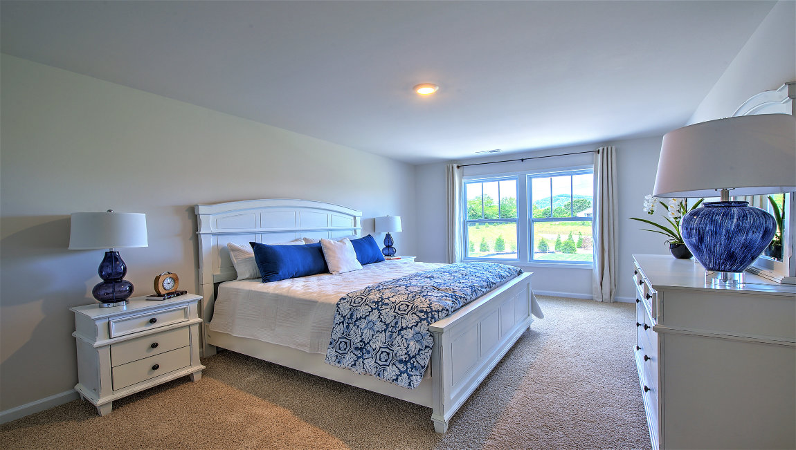 Carpeted primary bedroom with large windows