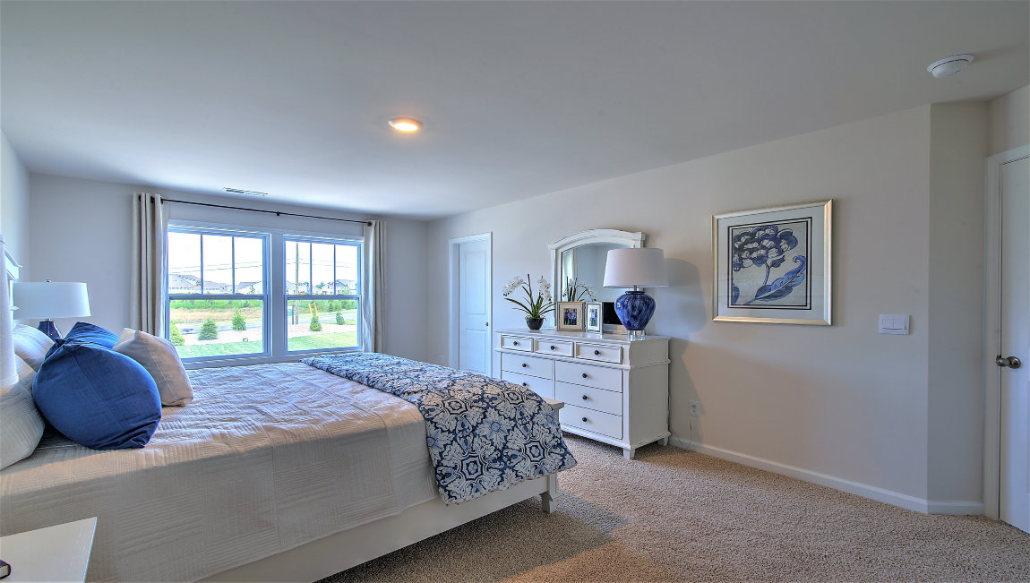 Carpeted primary bedroom with large windows