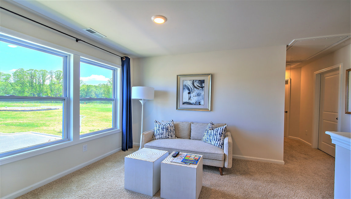 Carpeted loft area with large windows