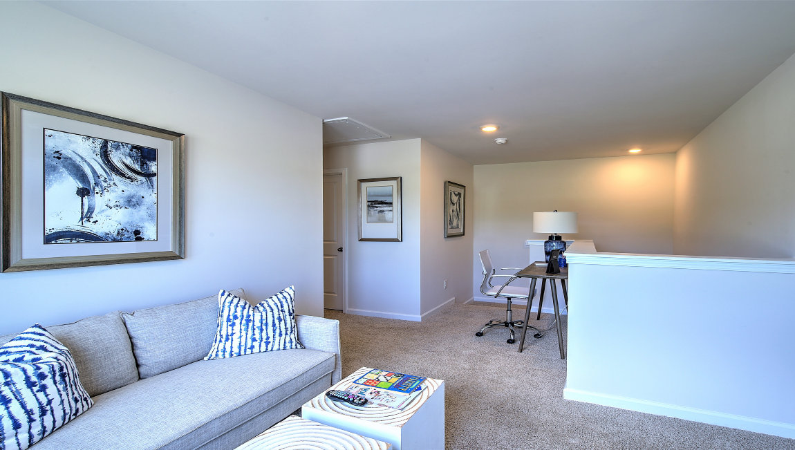 Carpeted loft area with stairwell view