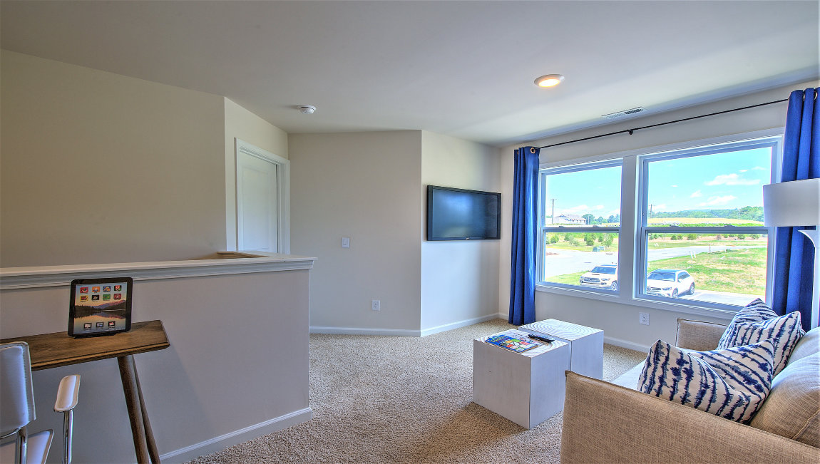 Carpeted loft area with large windows