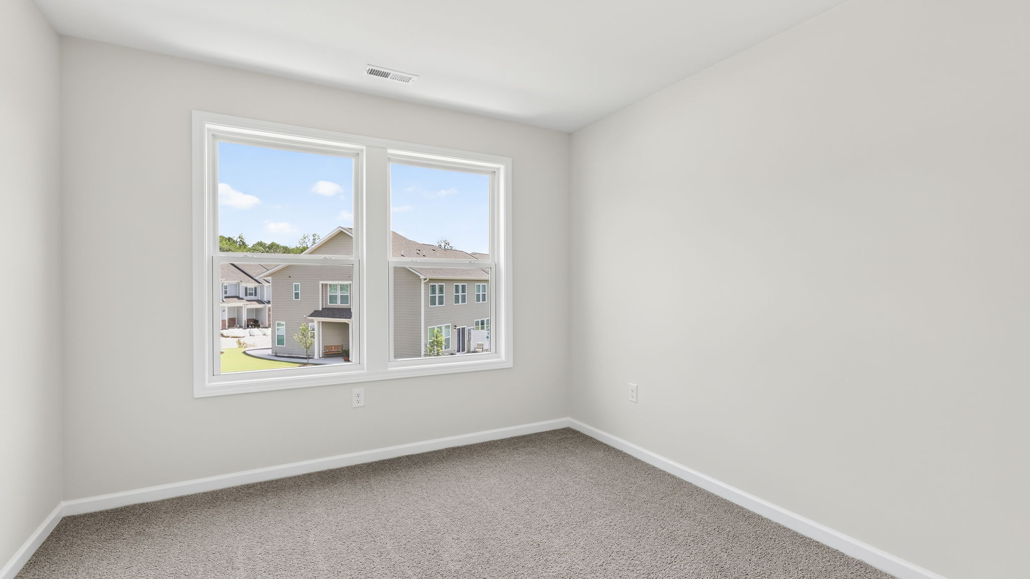 Carpeted primary bedroom with large windows