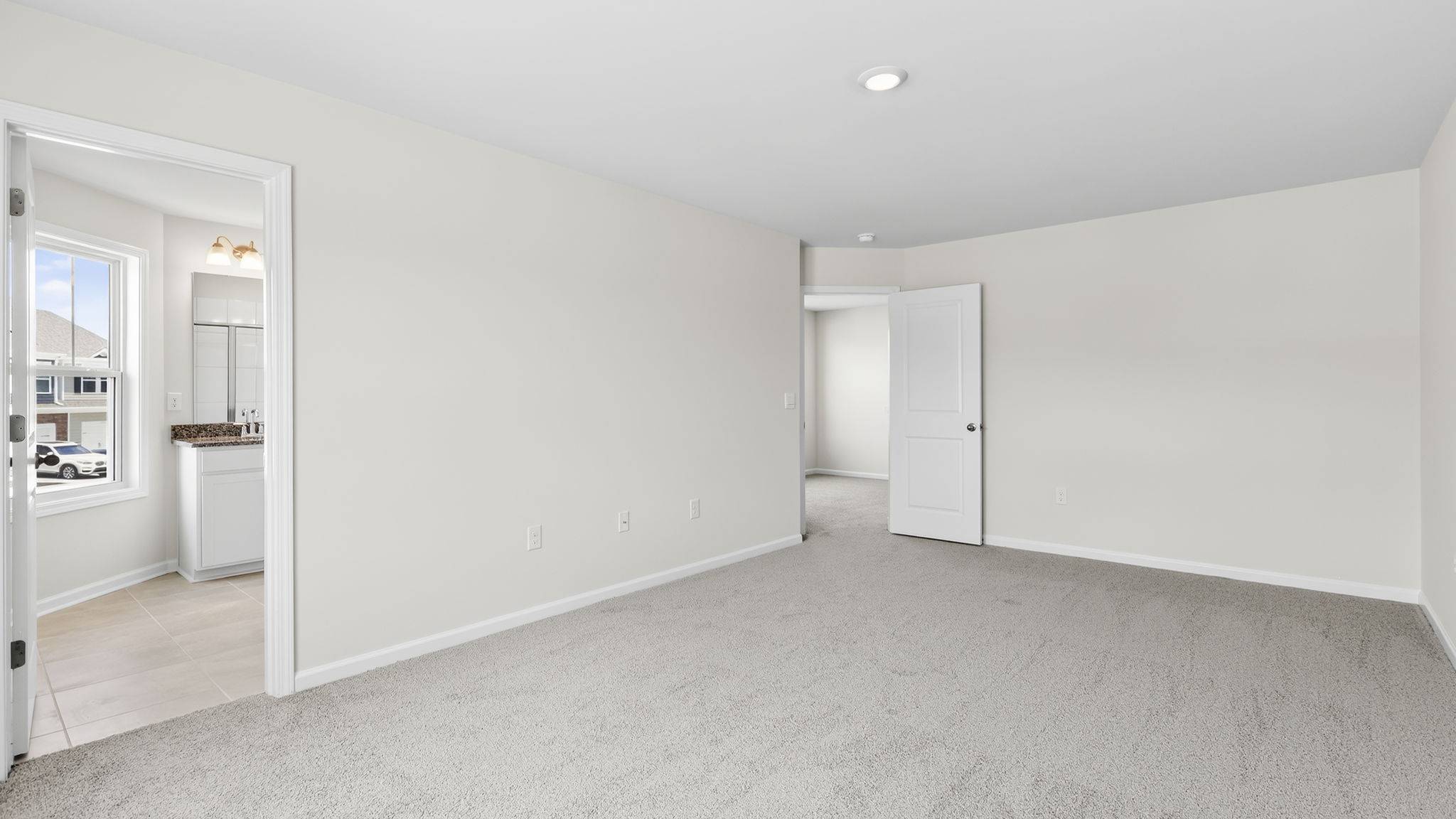 Carpeted primary bedroom with attached bathroom