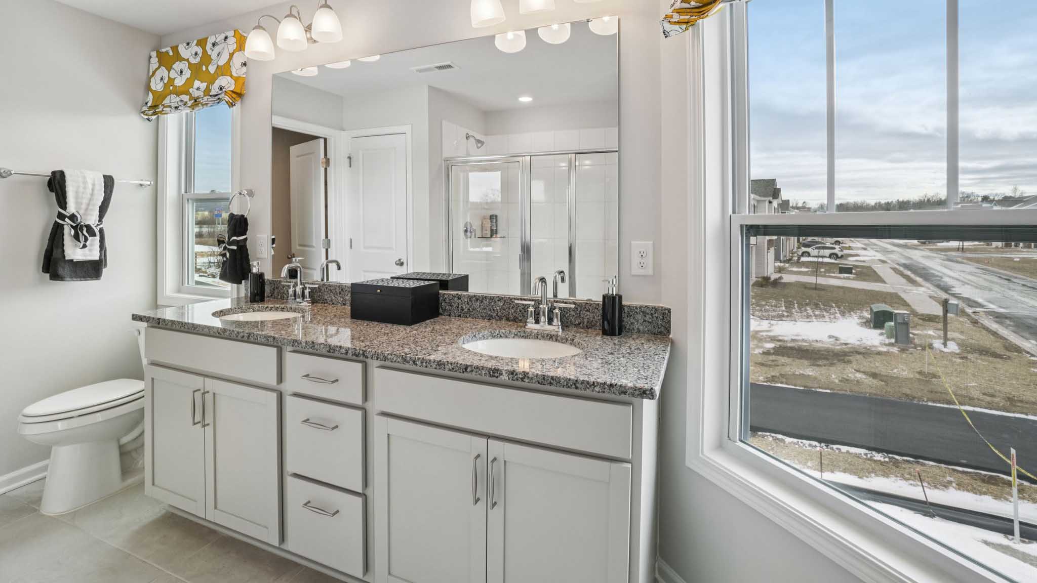 Primary bathroom with dual vanity and large window