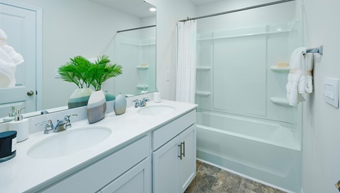 Bathroom with white cabinets and counters, and bathtub