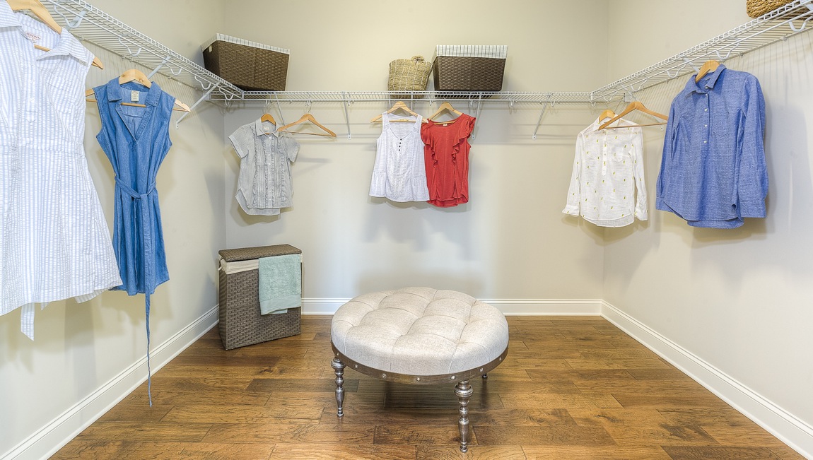 Primary bedroom walk in closet with wood floors and racks for hanging