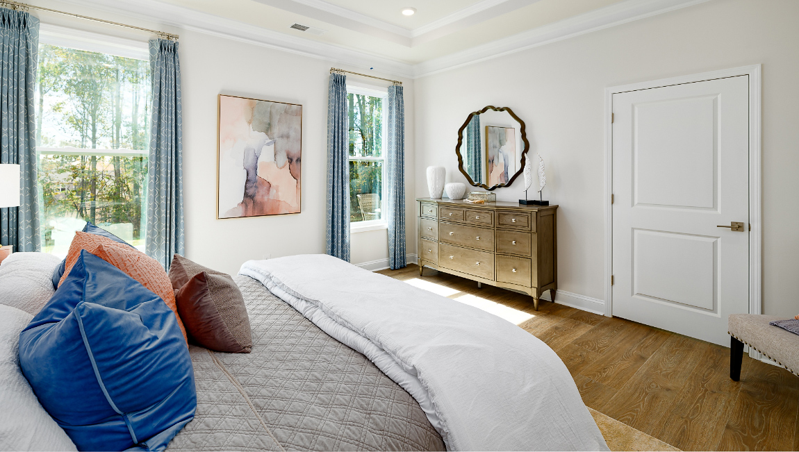 Primary bedroom with wood floors, and two large windows
