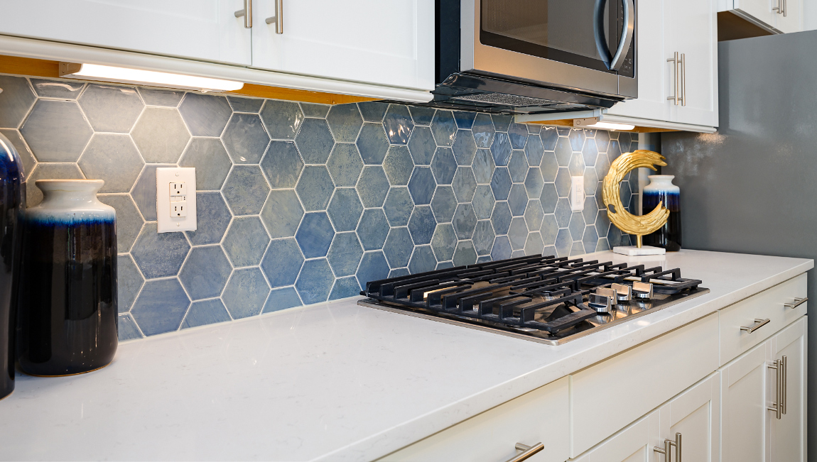 Kitchen and island with wood floors, white cabinets and counters, stainless steel appliances, and seating at island bar