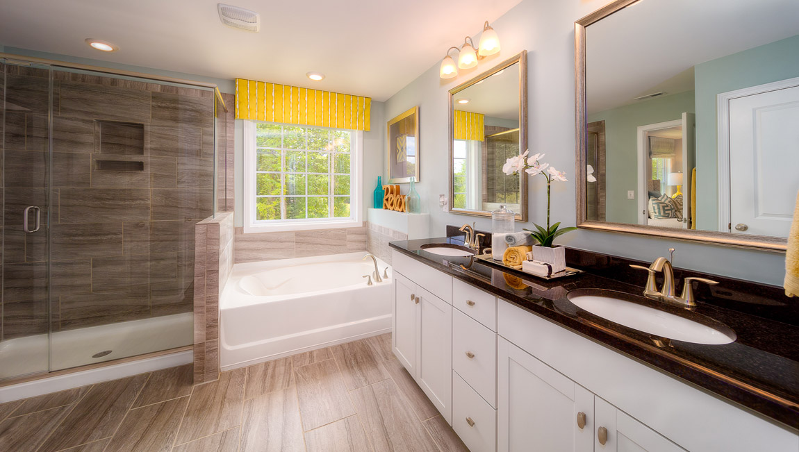 Primary bathroom with white cabinets, bathtub, and glass door shower