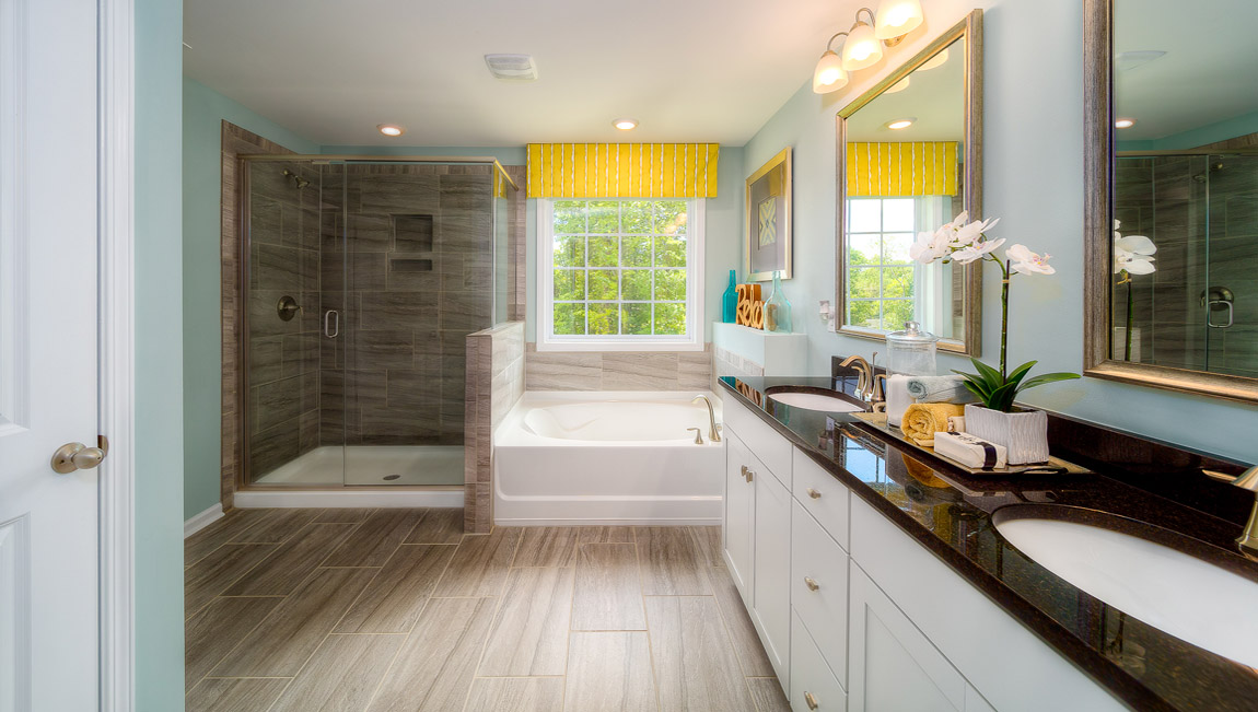 Primary bathroom with white cabinets, bathtub, and glass door shower