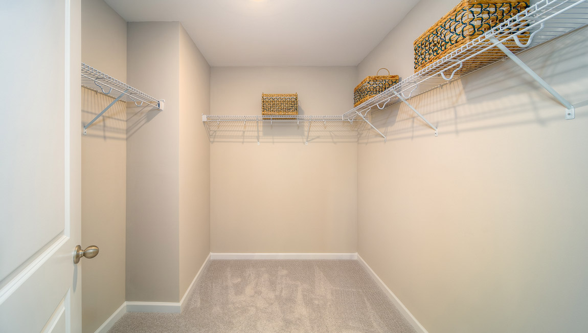 Primary bedroom walk in closet, carpeted