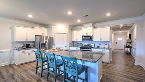 Kitchen and island, white cabinets, and stainless steel appliances