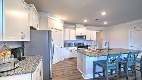 Kitchen and island, white cabinets, and stainless steel appliances