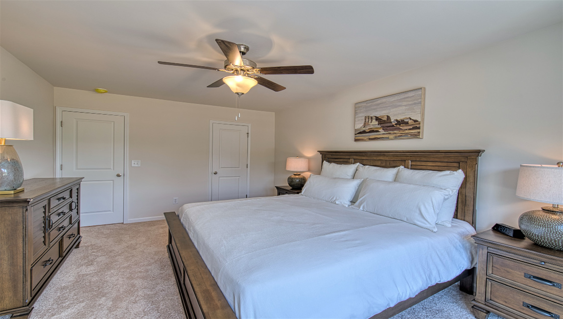 Carpeted primary suite with two large windows