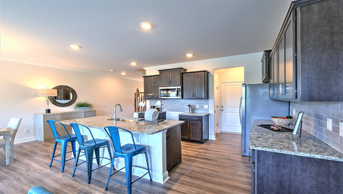 Open kitchen with island, wood floors, brown cabinets, living room in view