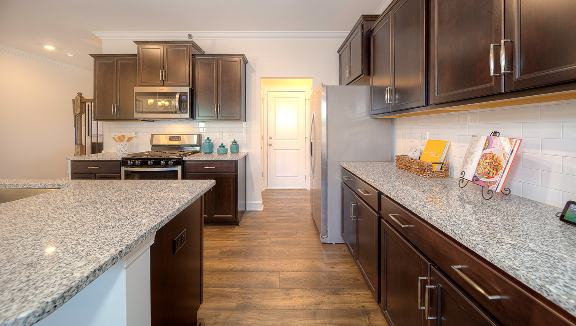 Open kitchen with island, wood floors, brown cabinets, living room in view