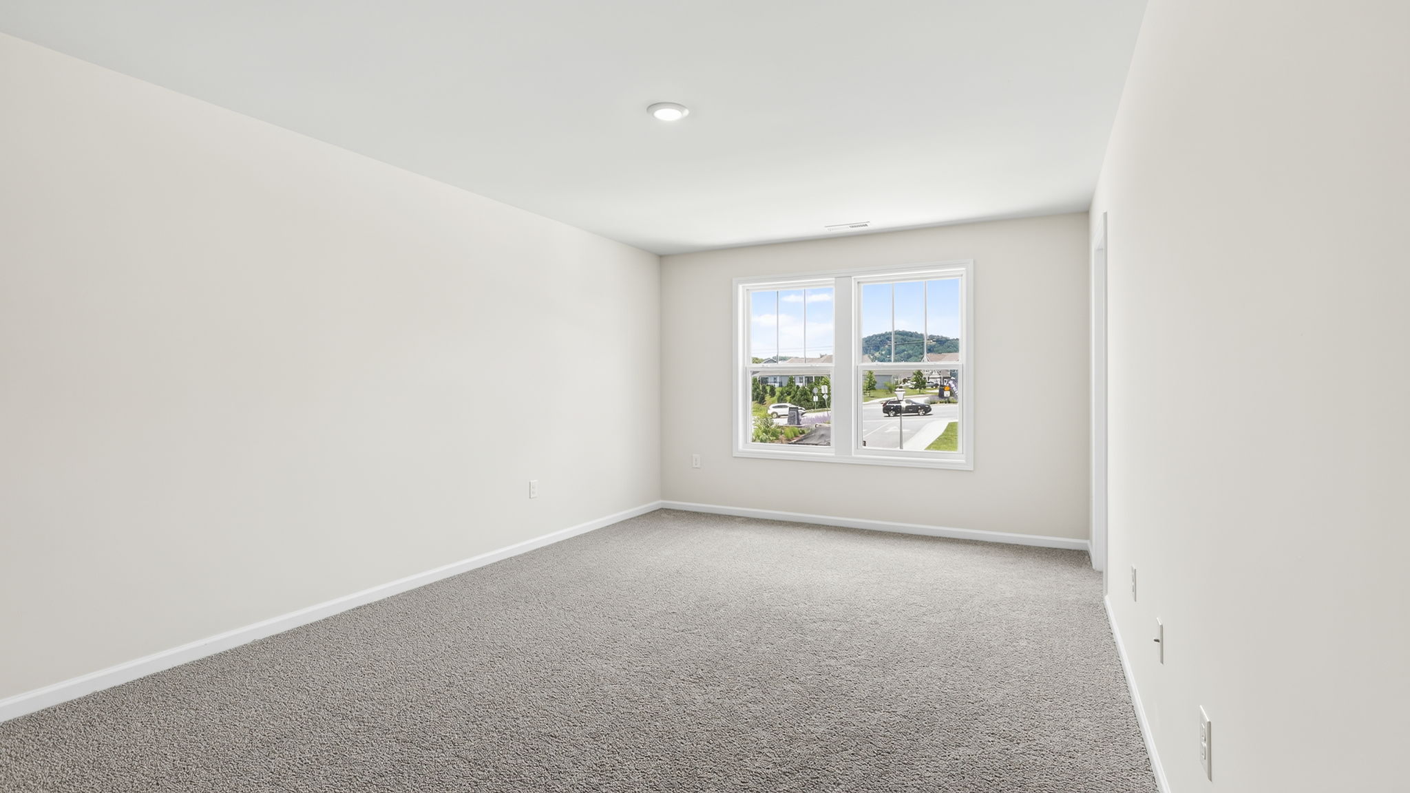 Carpeted primary bedroom with large windows