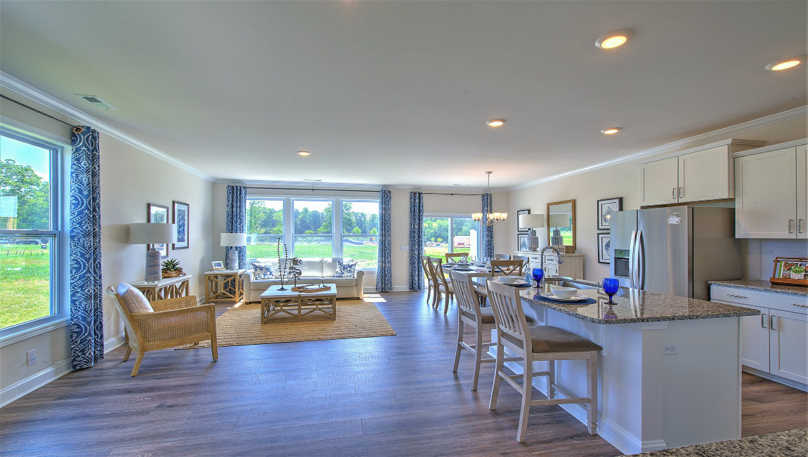 Open kitchen with island, wood floors, brown cabinets, living room in view