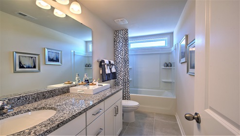 Bathroom with bathtub, white cabinets and large window