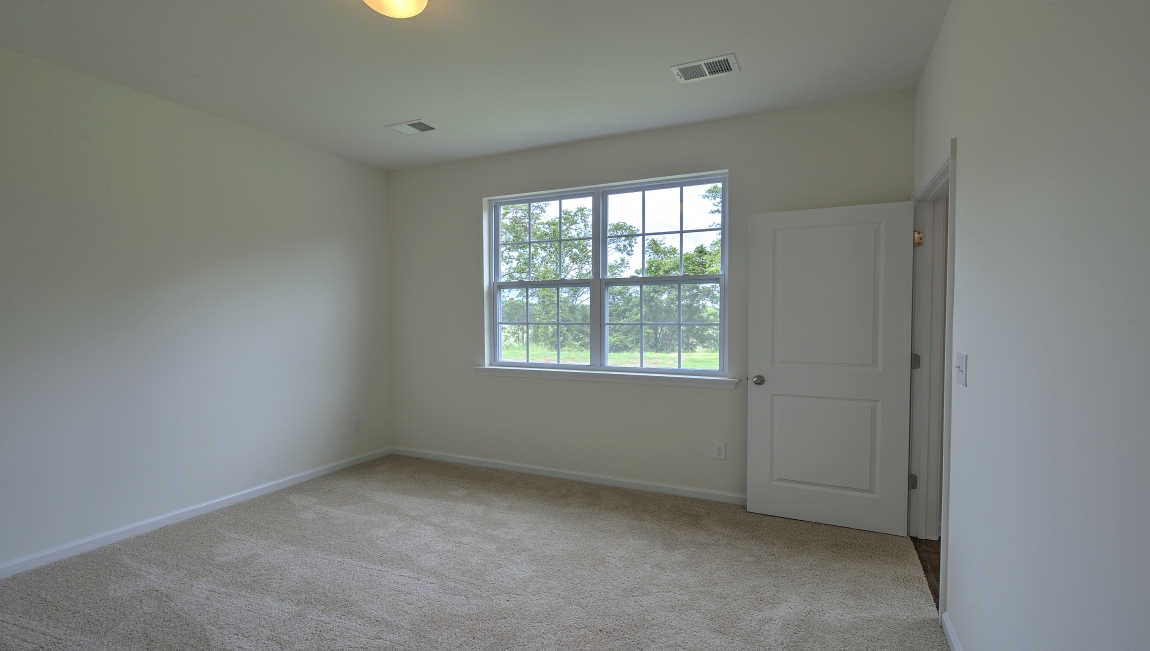 Primary carpeted bedroom with large window