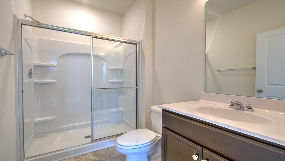 Primary bathroom with white counters and glass door shower
