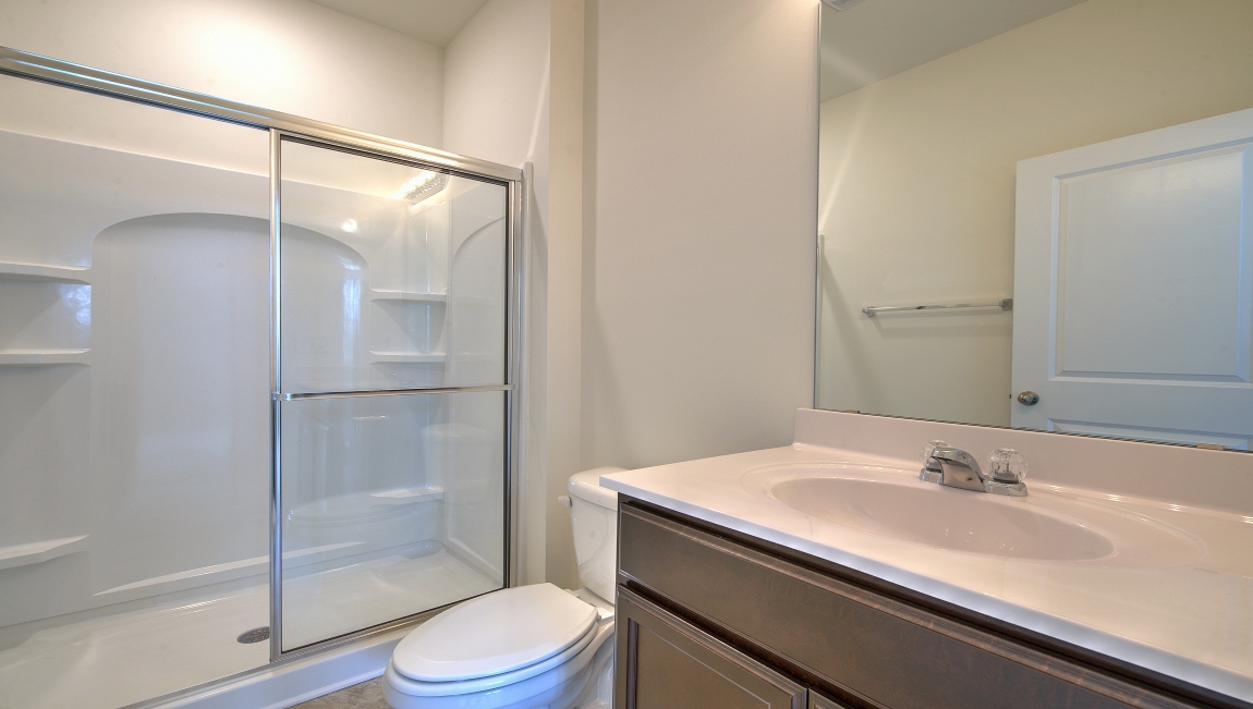 Primary bathroom with white counters and glass door shower