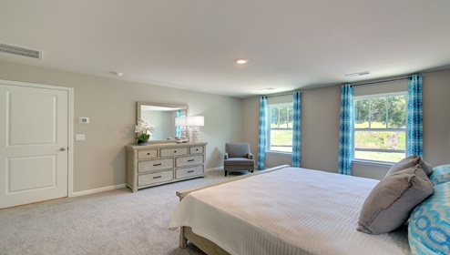Primary bedroom with beige carpeting and two large windows