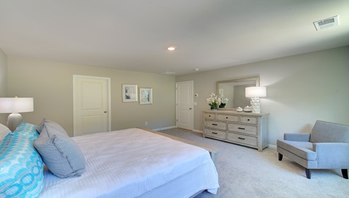Primary bedroom with beige carpeting and two large windows