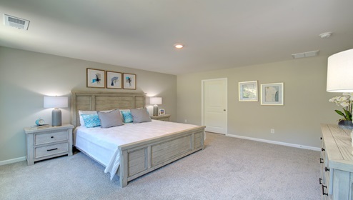 Primary bedroom with beige carpeting and two large windows