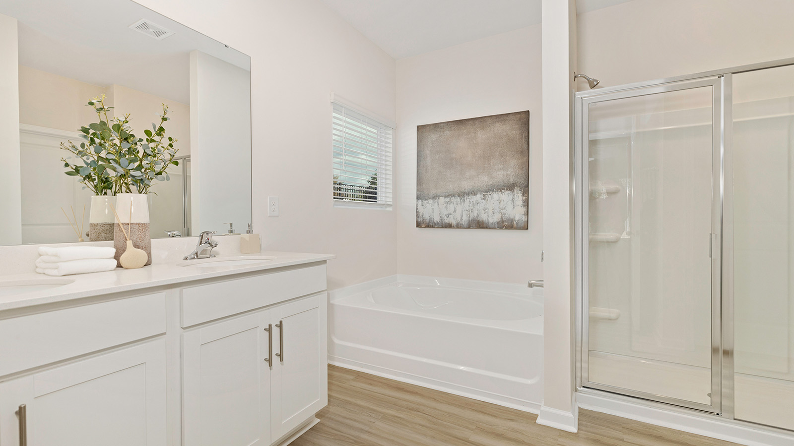 Bathroom with white cabinets and counters, and glass door shower