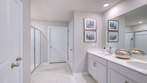 Primary bathroom with double sink vanity, white cabinets and counters, and standing glass door shower