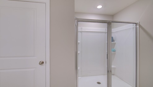 Primary bathroom with double sink vanity, white cabinets and counters, and standing glass door shower