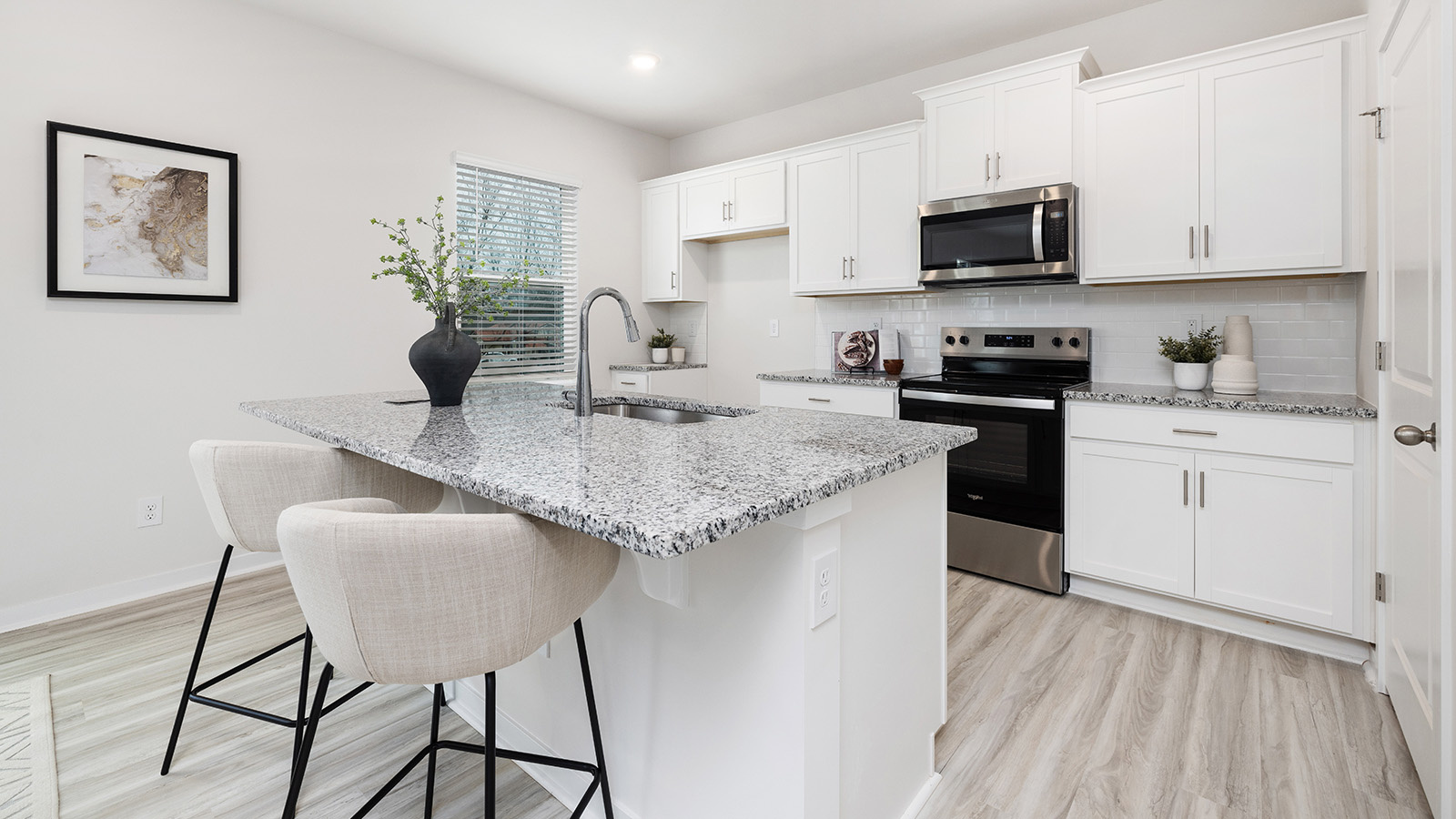 Kitchen with island, white cabinets and wood floors