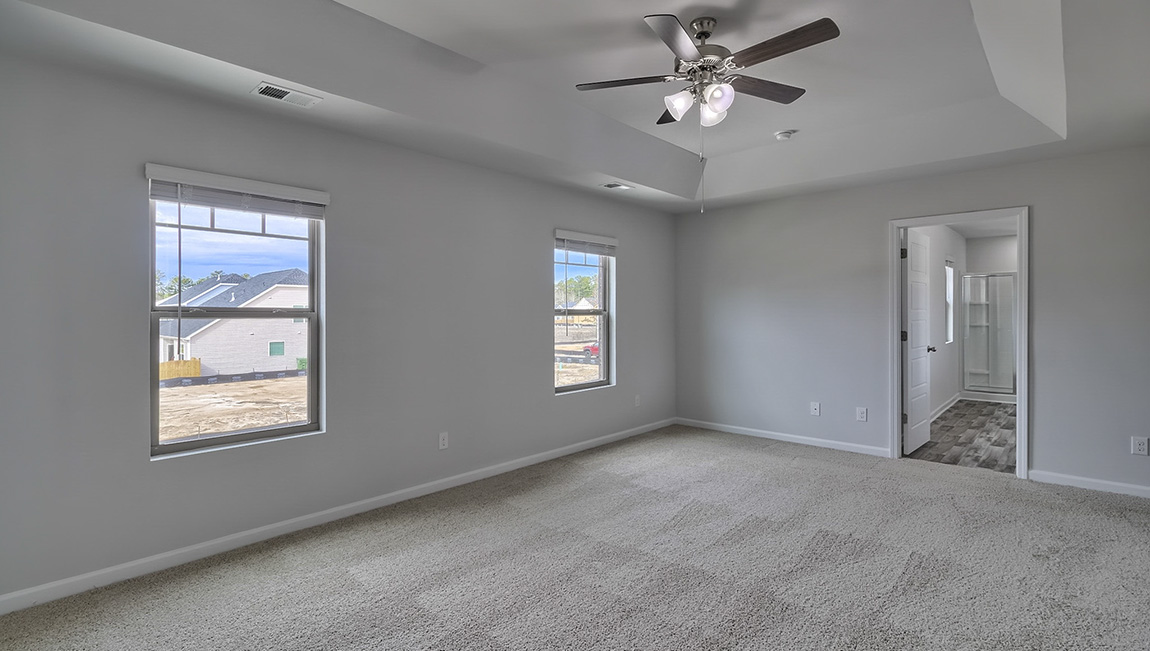Primary bedroom with carpet, ceiling fan and large windows
