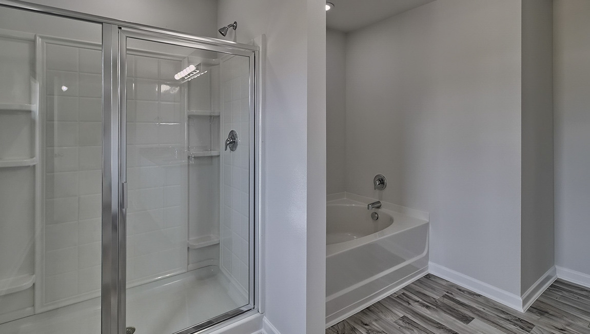 Primary bathroom with standing glass door shower, large bathtub, and double sink vanity